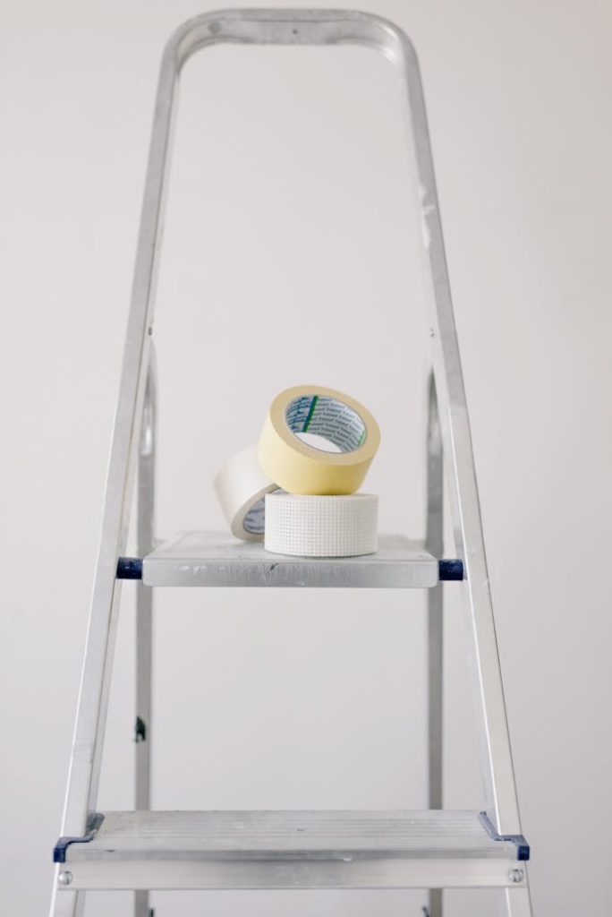 ladder-with-scotch-in-flat-during-renovation-5767931 Metal stepladder with rolls of tape for home renovation projects.